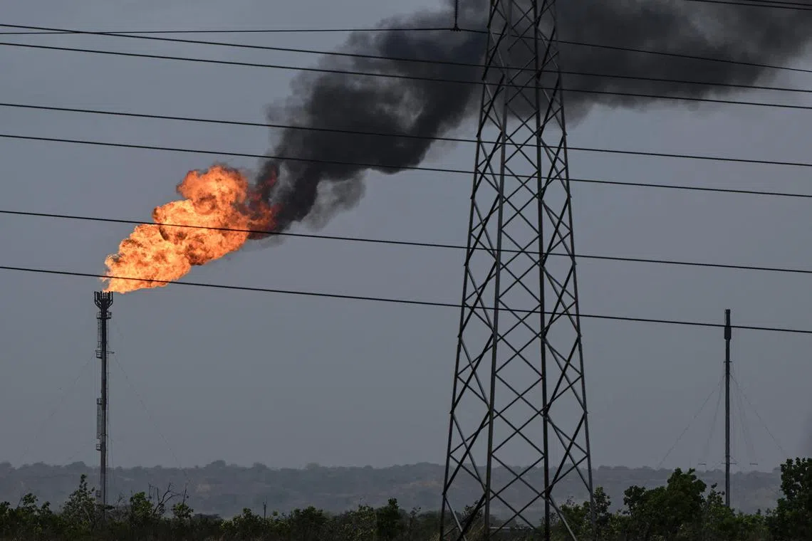 (FILES) The flame from a chimney of an oil refining plant is seen along the highway between El Furrial and Maturin in Monagas state, Venezuela on April 7, 2023. Venezuela on January 30, 2024, slammed Washington's decision to reimpose oil and gas sanctions as "rude and improper blackmail", and threatened to halt deportation flights for Venezuelan migrants who are in the United States illegally. (Photo by Yuri CORTEZ / AFP)