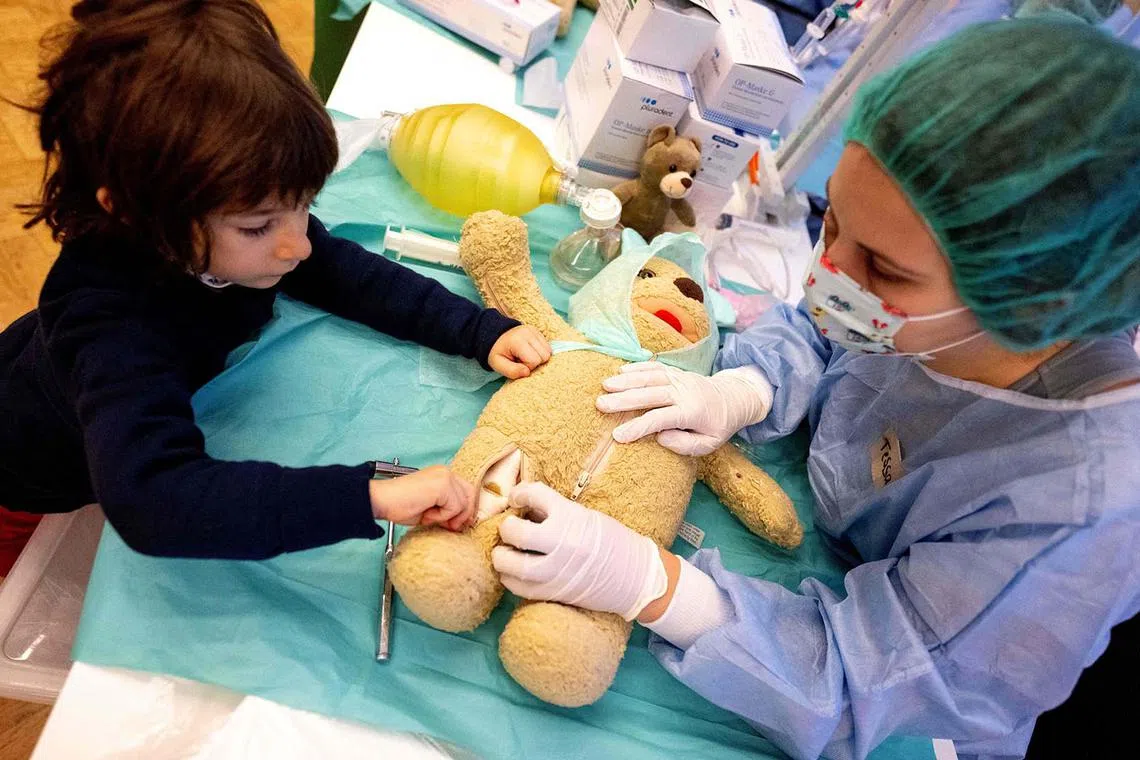 TOPSHOT - Medic Tessa (R) and 4-year-old Dian operate a teddy bear during the 'Teddy Bear Hospital' event organized by the Vienna Medical Association in Vienna, Austria on December 5, 2023. Approximatly 60 medics participated in the campaign intended to allay children's fears of visiting the doctor or being hospitalized. (Photo by Joe Klamar / AFP)