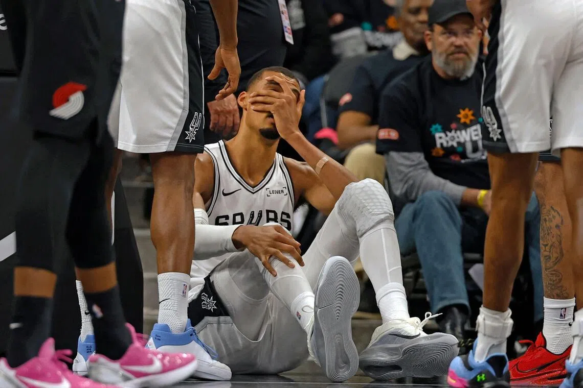Victor Wembanyama of the San Antonio Spurs holds his head after falling to the court against the Portland Trail Blazers in the first half of Game Two.