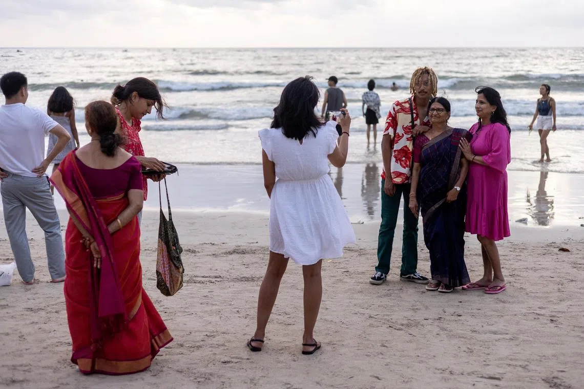 Tourists from India walk and take pictures at Patong beach in the island of Phuket, Thailand.