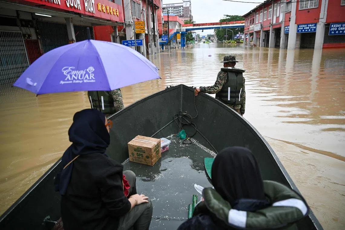Malaysian army soldiers use a boat to transport residents in the flooded town of Kota Tinggi in Malaysia's Johor state.