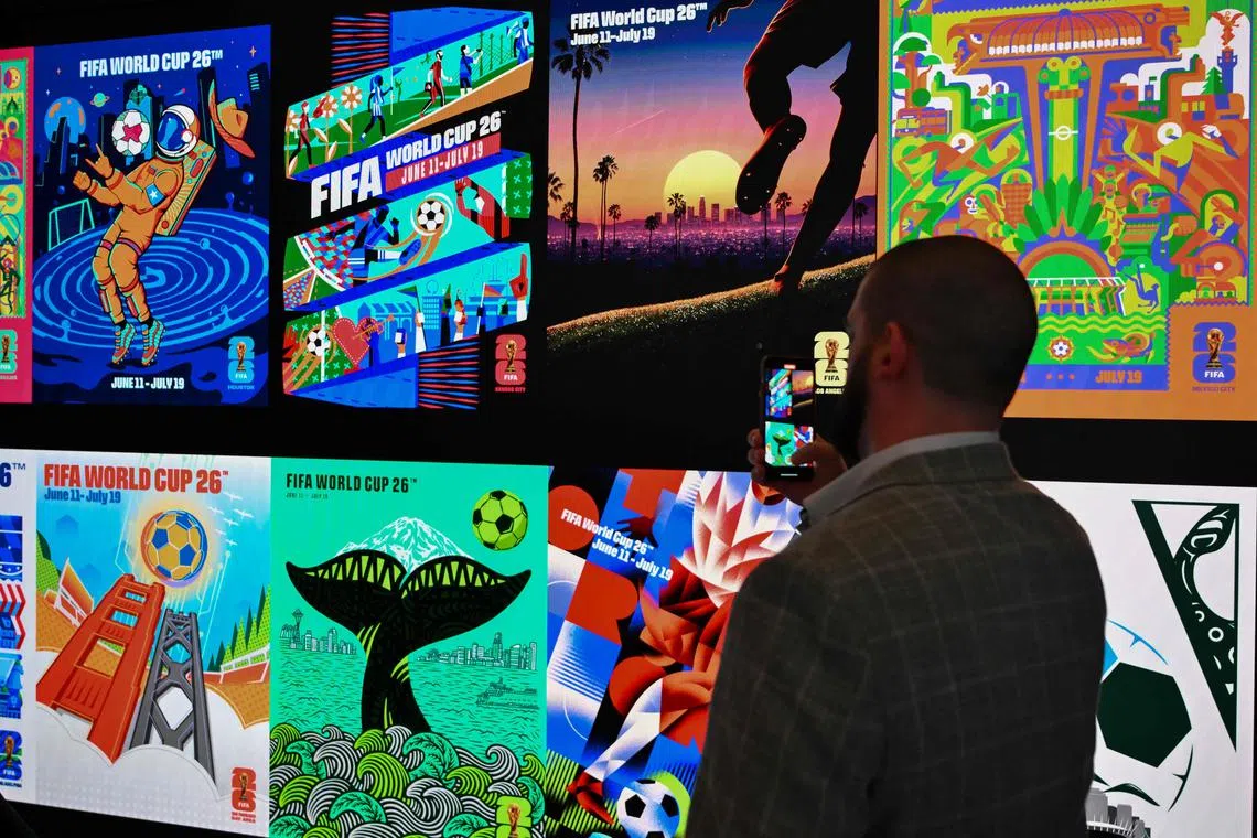 A person takes a picture of artwork for the various host cities of the 2026 FIFA World Cup.
