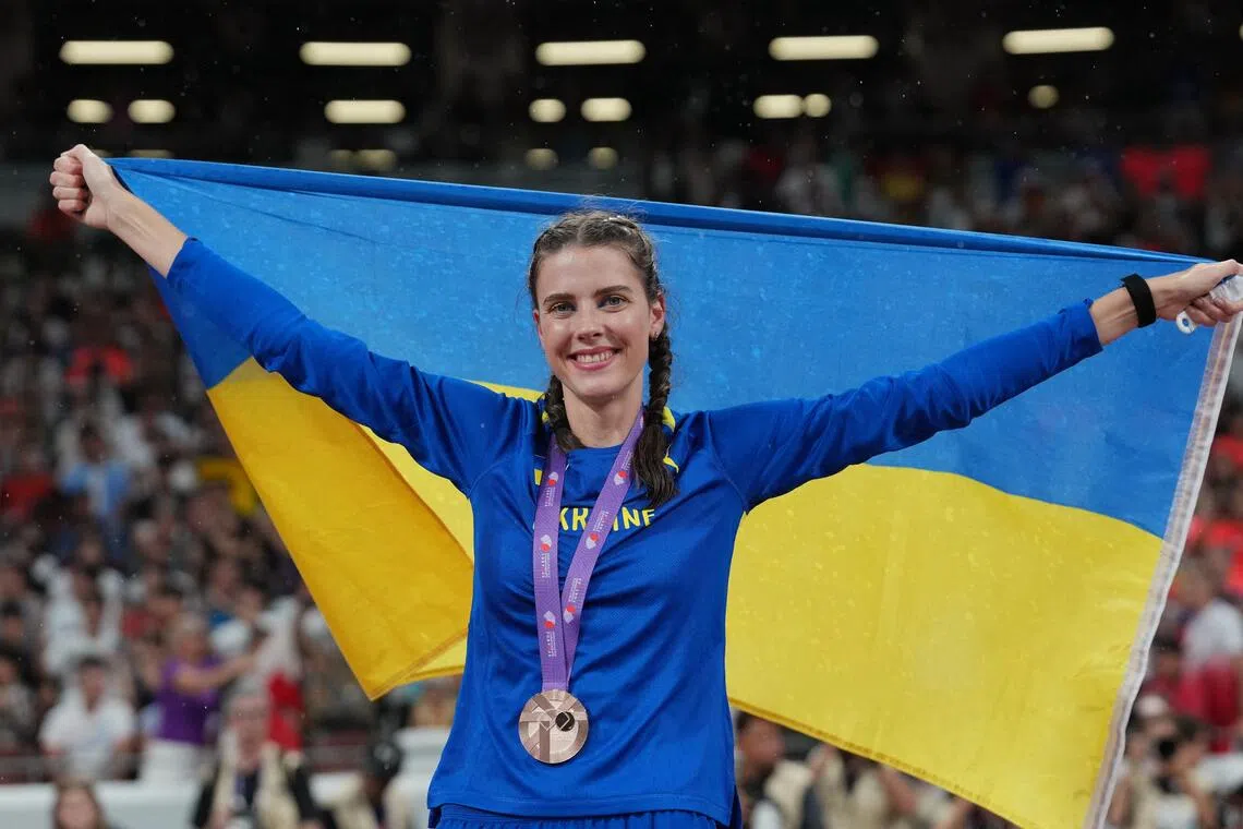 Ukraine's Yaroslava Mahuchikh celebrates with her medal and national flag after winning bronze in the high jump final at the World Championships.