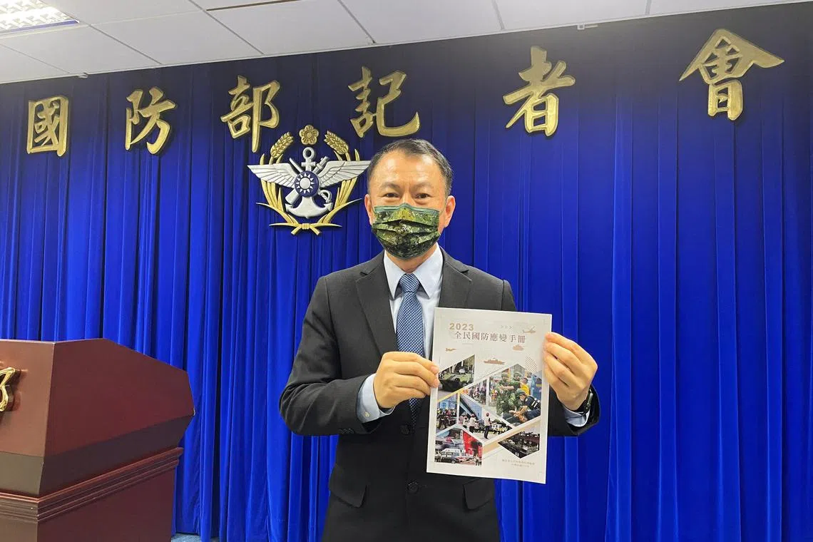 All-Out Defence Mobilisation Agency Director Shen Wei-chih holding a copy of the updated civil defence handbook.