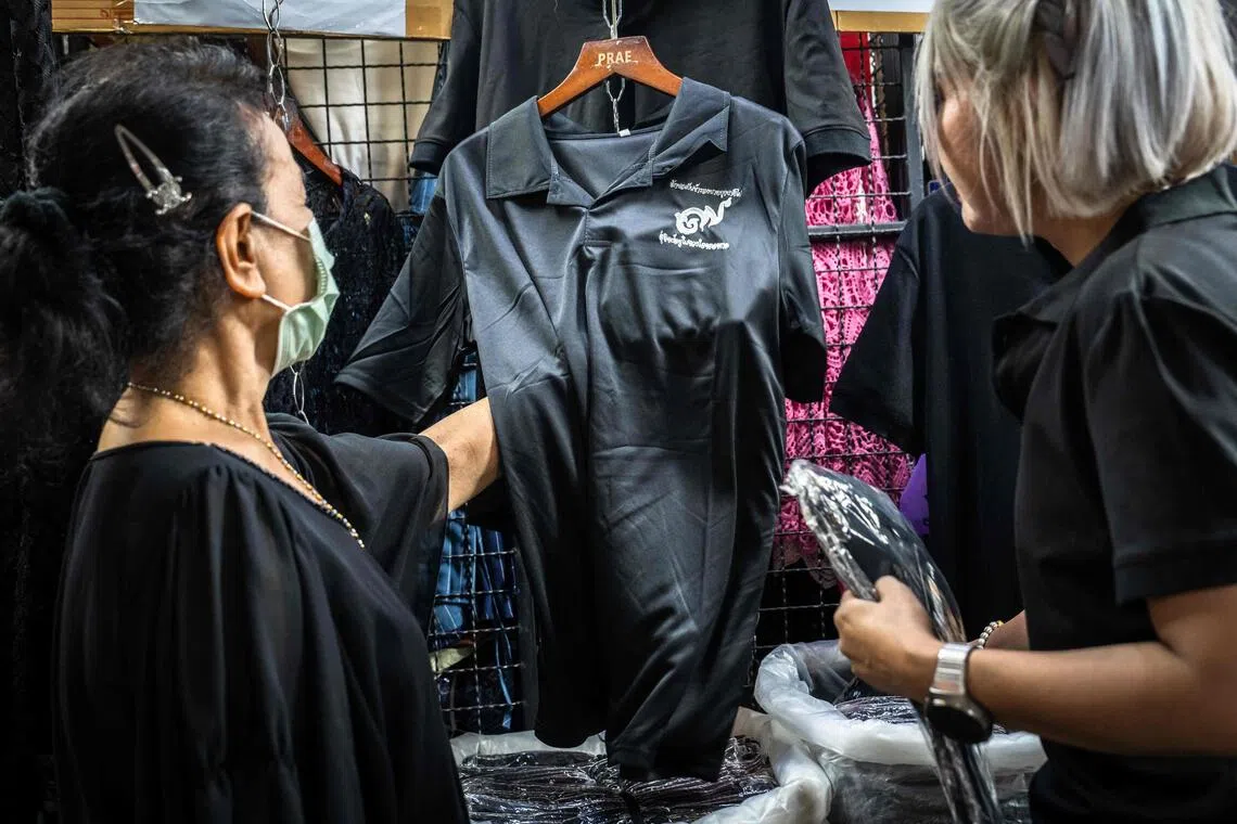 Customers browse for black clothing to mourn the death of Thailand's former queen Sirikit at a store in Bangkok on October 30, 2025. The government has declared a year-long mourning period for officials and urged the public to wear traditional Thai mourning colours of black or white for 90 days. (Photo by Chanakarn Laosarakham / AFP)