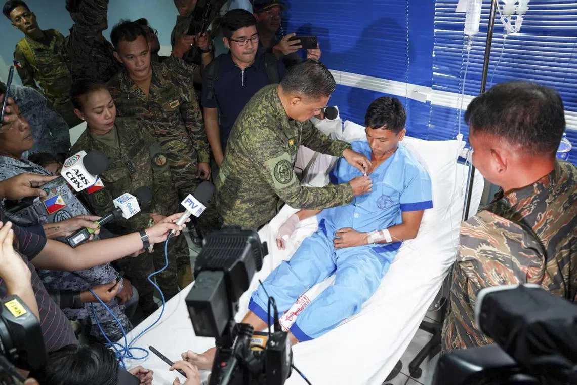 Philippine military chief Romeo Brawner Jr pins a medal on a navy personnel wounded during a skirmish with the Chinese coast guard near a disputed atoll in the South China Sea.