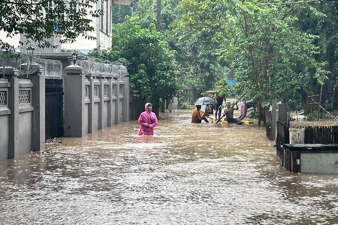 People make their way through floodwaters covering a street in Myitkyina in Myanmar's northern Kachin state on July 2.