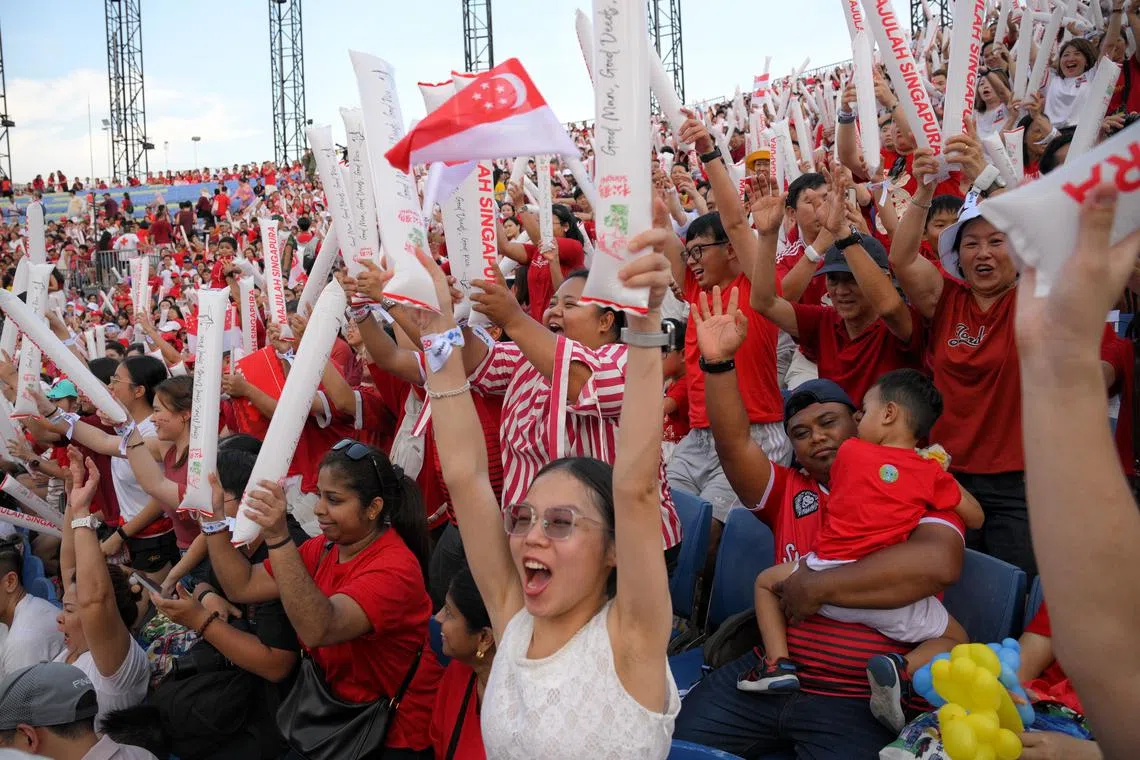 Spectators doing the Kallang Wave during the National Day Parade at the Padang. With a population now having bought into the aspirations of the National Pledge, realising it through lived experiences is needed for the next stages of nation-building, says the writer.