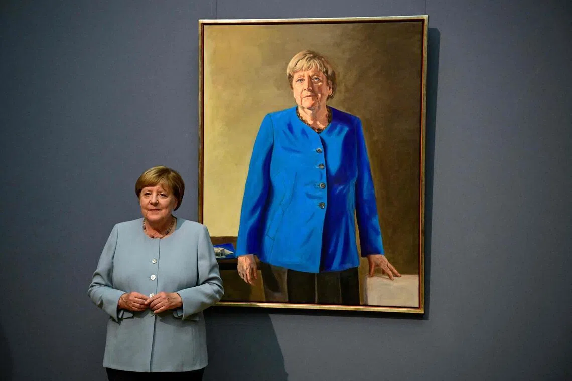Former German chancellor Angela Merkel stands next to French-German artist Jeremie Queyras’ painting ‘Portrait of former Federal Chancellor Angela Merkel’ at the Bode Museum in Berlin, on June 30.