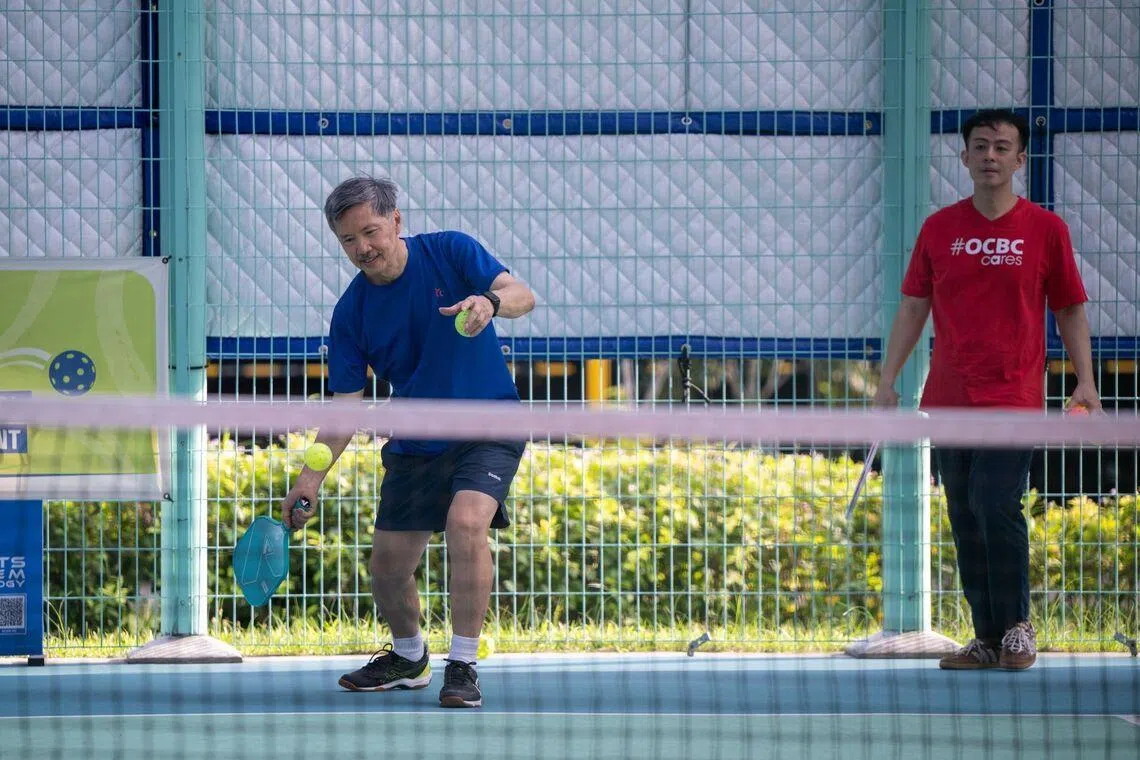 Alvin Chan, 66, participating in a friendly pickleball rally as OCBC volunteer Jonathan Chua supports from the sidelines. The training sessions are structured to help seniors progressively learn the fundamentals and rules of the sport.