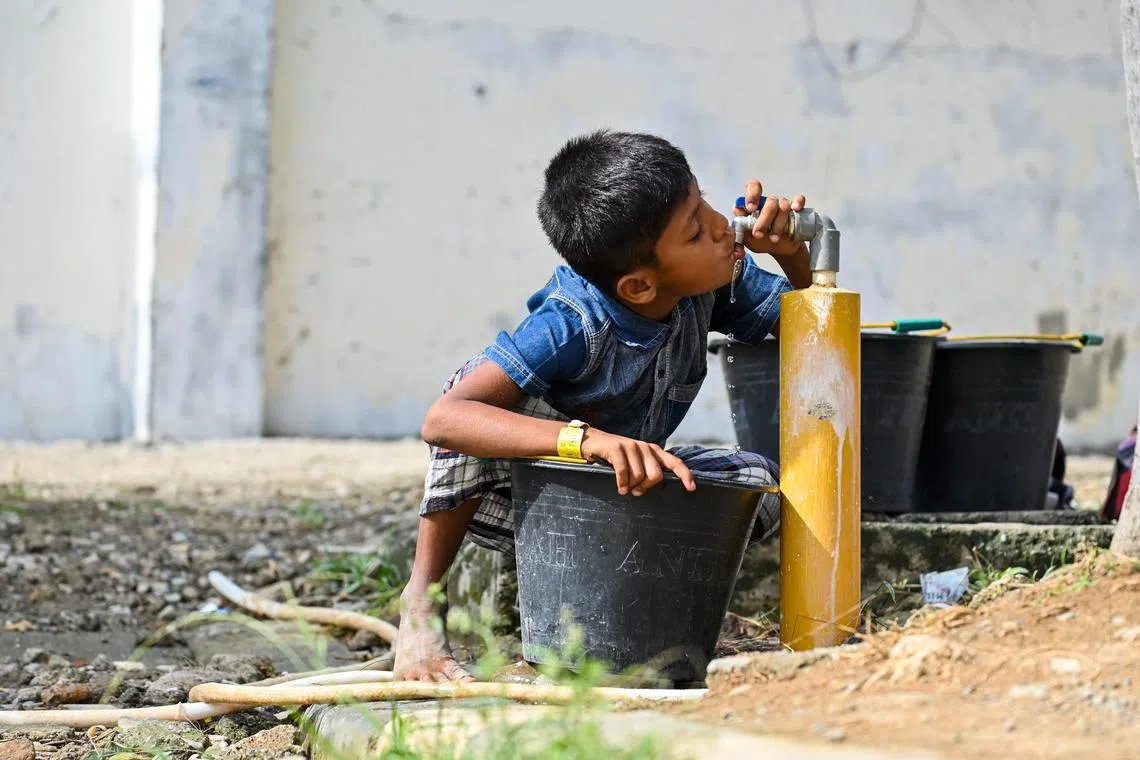 TOPSHOT - A Rohingya refugee Child drinks from a water tap at a temporary shelter at a government building in Banda Aceh on January 11, 2024. (Photo by CHAIDEER MAHYUDDIN / AFP)