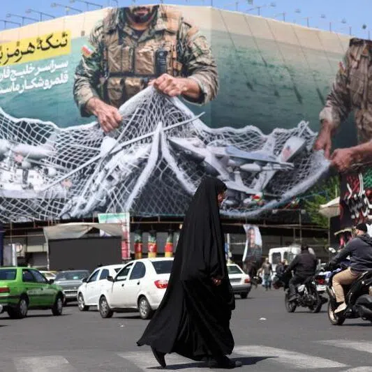 Commuters make their way past a billboard with a sentence reading ‘The Strait of Hormuz remains closed’ at the Enqelab Square in Tehran, on April 5, 2026. Oman and Iran held talks on easing passage through the Strait of Hormuz, the Omani state news agency reported on April 5, with the key shipping chokepoint effectively closed due to war in the Middle East. 