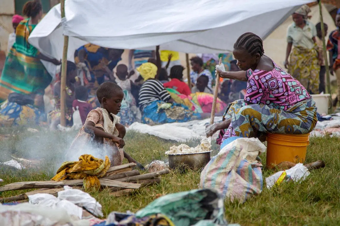 FILE PHOTO: A Congolese woman prepares a meal near a temporary shelter at Rugombo Stadium, after fleeing from renewed clashes between M23 rebels and the Armed Forces of the Democratic Republic of the Congo (FARDC), in Rugombo commune of Cibitoke Province, Burundi February 18, 2025. REUTERS/Evrard Ngendakumana/File Photo
