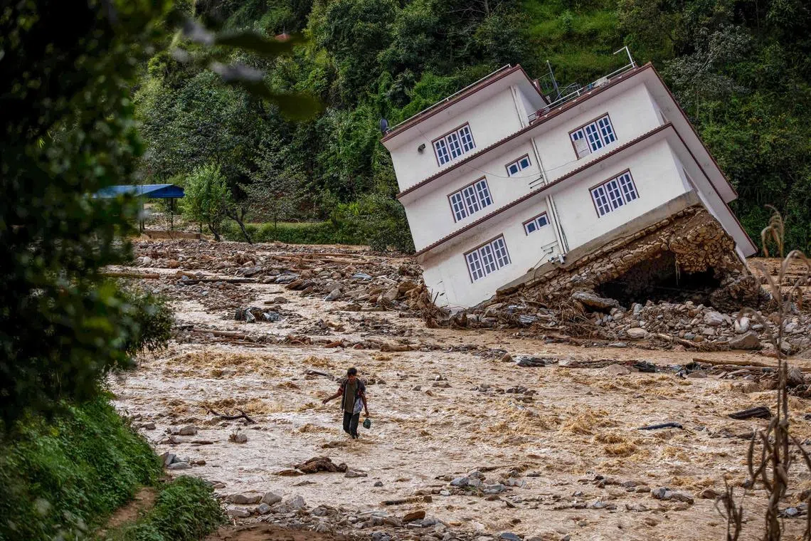 A man wades through the flood waters in the affected area of monsoon flooding in Roshi village of Nepal's Kavre district on Sept 30.