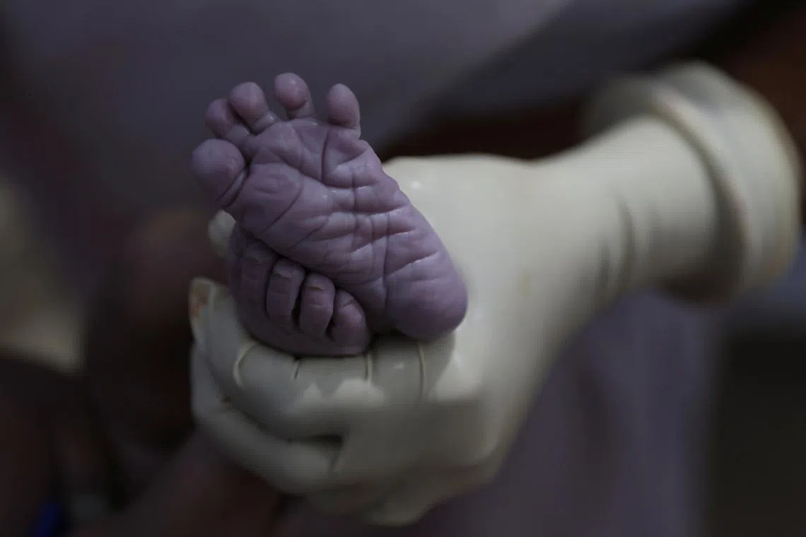A nurse holding the feet of a newborn baby after it was delivered at the labour ward of a community health centre in Bahadurganj subdivision on March 21.