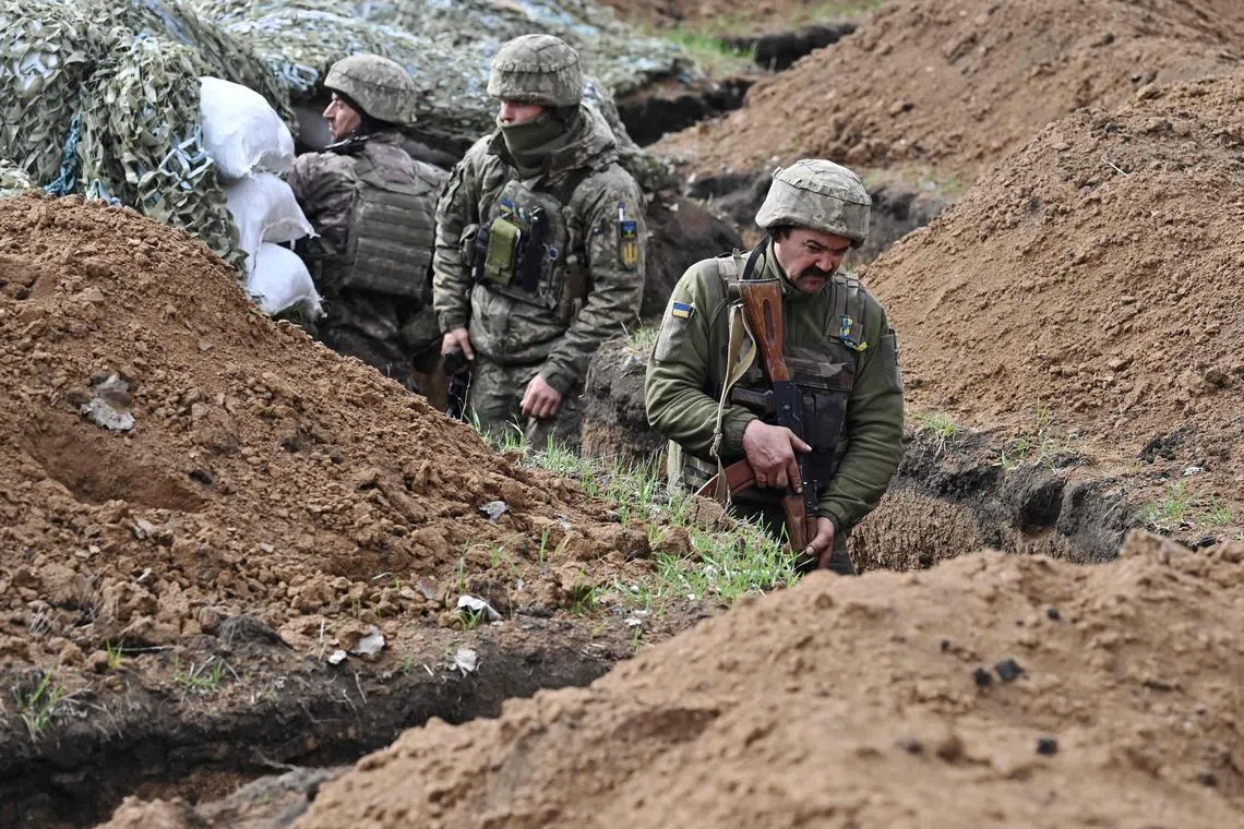 Ukrainian servicemen stand in a trench near the town of Bakhmut, in Ukraine's Donetsk region.