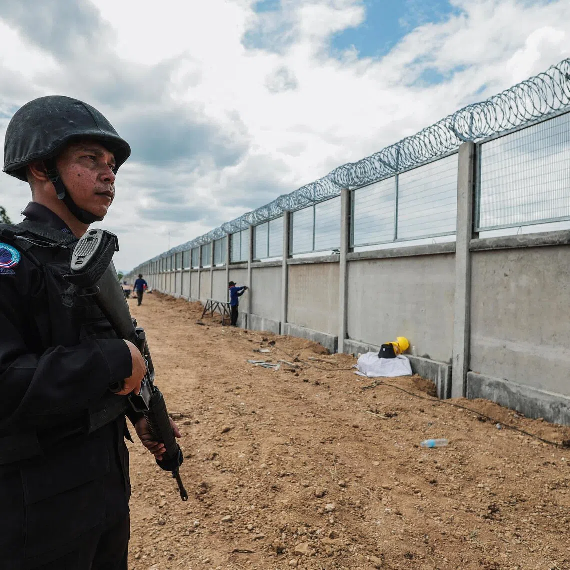 A Thai soldier stands guard as workers construct a section of the border fence between Thailand and Cambodia in Pong Nam Ron district, Chanthaburi province.