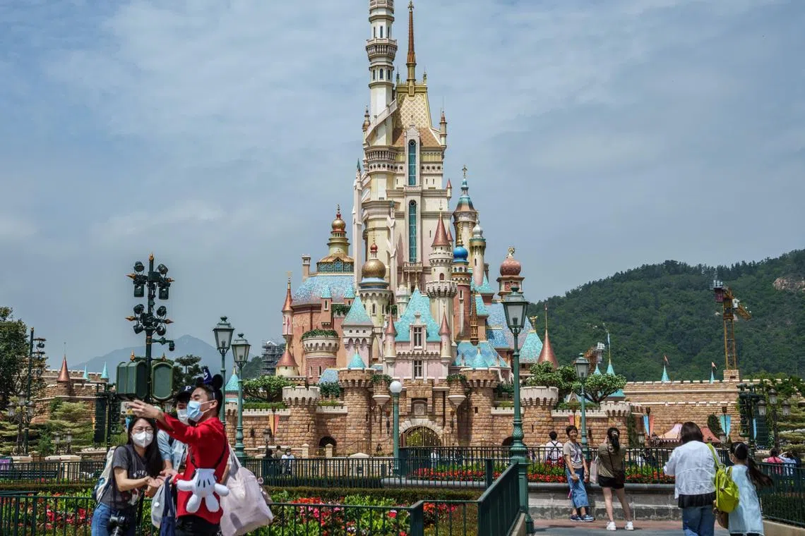 Visitors wearing protective masks take pictures in front of the Castle of Magical Dreams at Walt Disney Co.'s Disneyland Resort during its reopening in Hong Kong, China, on Thursday, April 21, 2022. With daily new infections now numbering in the hundreds, rather than the tens of thousands, the focus turns to how far Hong Kong will go in opening up to the rest of the world and whether it can retain its role as an international finance hub. Photographer: Lam Yik/Bloomberg