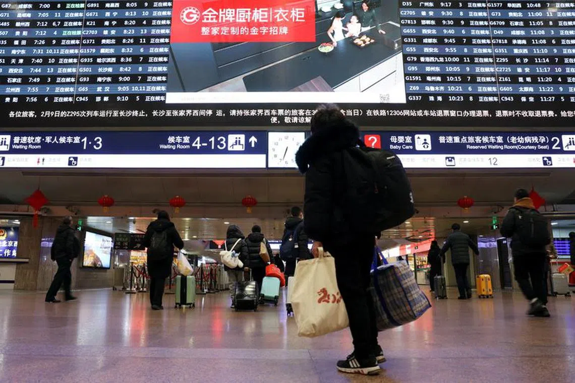 A traveller checks a display of train information at Beijing West railway station during the Spring Festival travel rush on Lunar New Year's Eve, in Beijing, China February 9, 2024. REUTERS/Florence Lo