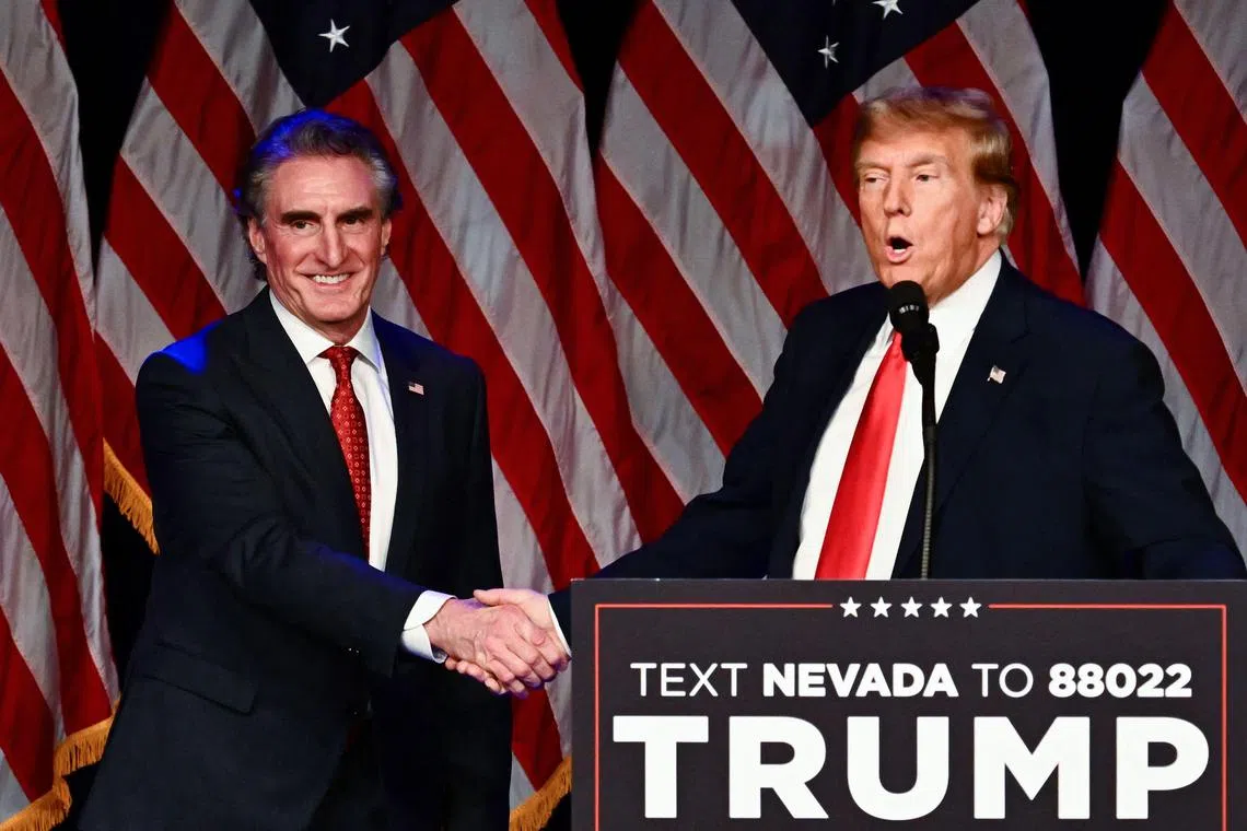 (FILES) Kathryn Burgum aplauds as her husband Republican Governor of North Dakota Doug Burgum shakes hands with former US President and 2024 presidential hopeful Donald Trump during a Caucus Night watch party in Las Vegas, Nevada, on February 8, 2024. US President-elect Donald Trump announced on November 14, 2024 his intention to nominate Governor of North Dakota Doug Burgum as the US Secretary of the Interior. (Photo by Patrick T. Fallon / AFP) / ALTERNATE CROP