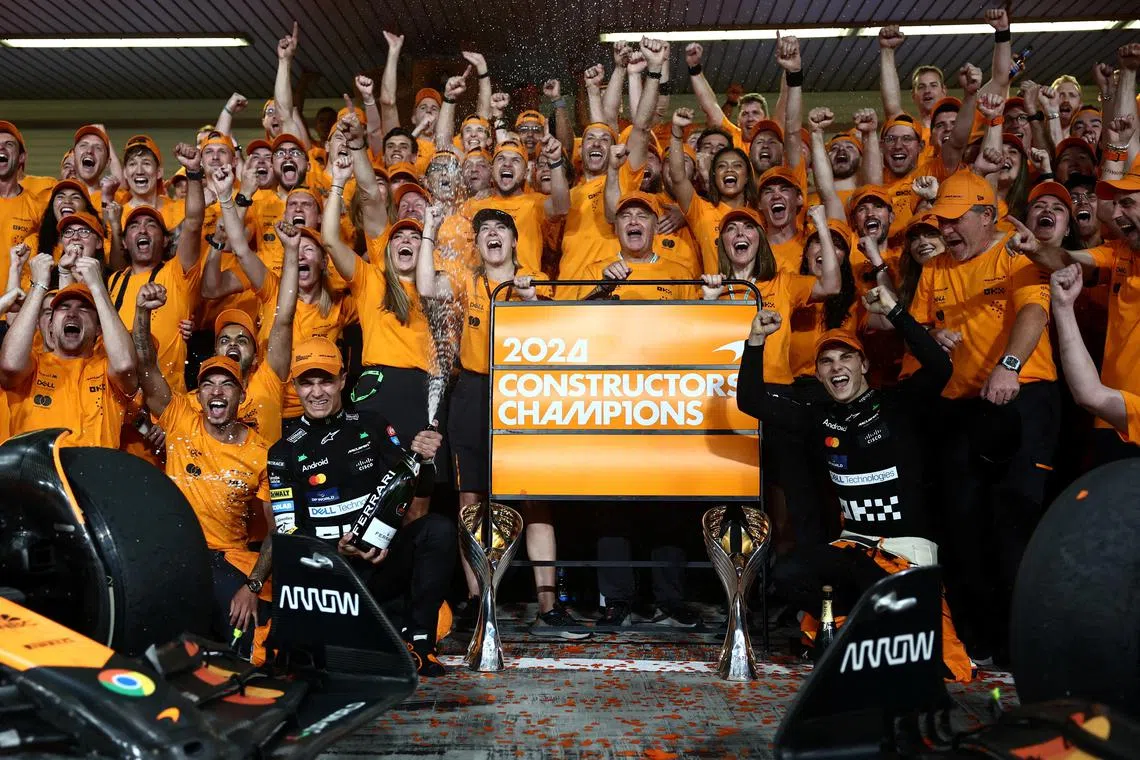 McLaren's Lando Norris and McLaren's Oscar Piastri celebrate with their teammates after Norris wins the Abu Dhabi Grand Prix and McLaren the constructors' title.