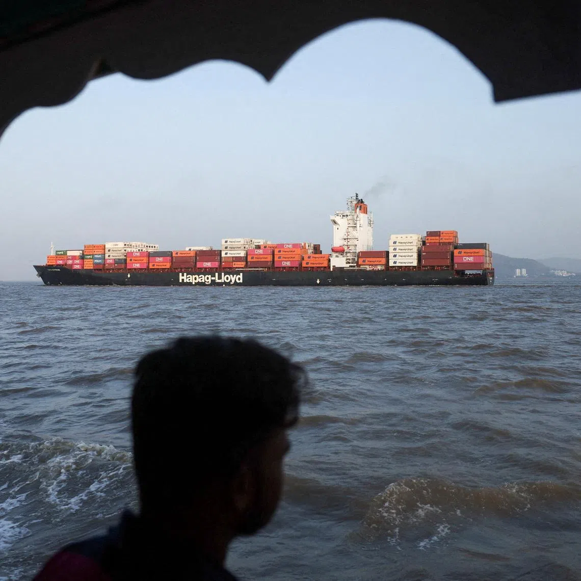 FILE PHOTO: A man looks at a container ship in the Arabian Sea off the coast of Mumbai, India, May 6, 2026. REUTERS/Francis Mascarenhas/File Photo