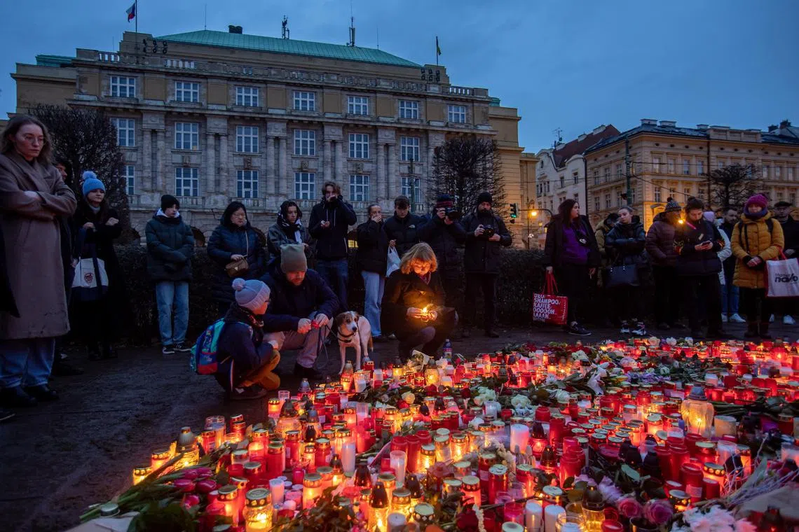 People pay their respects outside the building of the Philosophical Faculty of Charles University on Dec 22 following a mass shooting the day before in central Prague, Czech Republic.