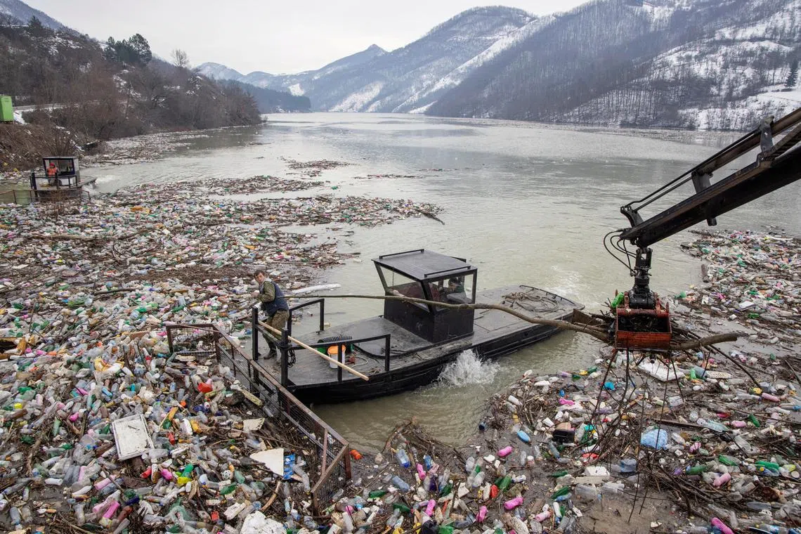 FILE PHOTO: A worker collects plastic trash that litters the polluted Potpecko Lake near a dam's hydroelectric plant near the town of Priboj, Serbia, January 29, 2021. REUTERS/Marko Djurica/File Photo