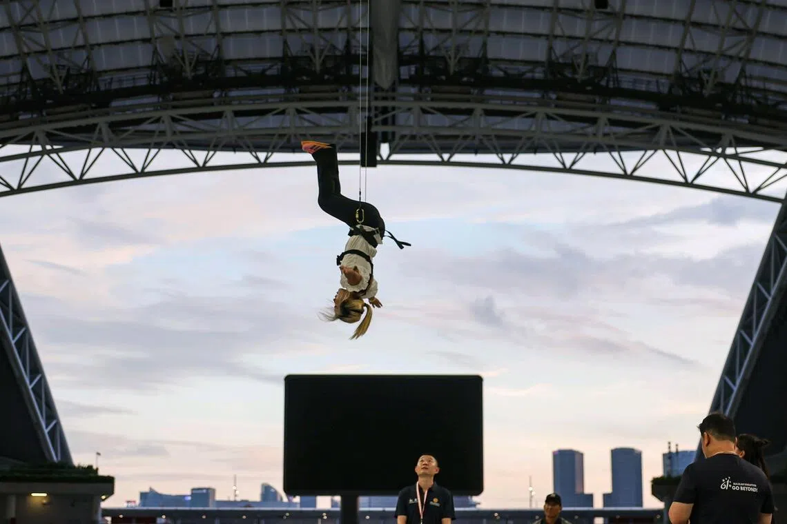 ST journalist Gabrielle Chan attempting the aerial experience during the NDP aerial performance media feature at the National Stadium on July 6.