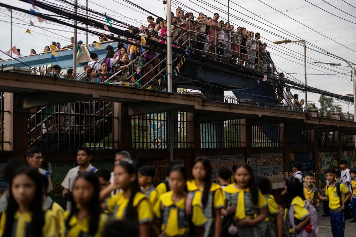 Parents and guardians watching over their children from a footbridge on the first day of classes at the President Corazon C. Aquino Elementary School in Quezon City, Philippines, on June 8, 2026. 