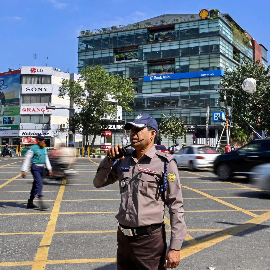 This photograph taken on Nov 16 shows a Bangladesh Police personnel wearing the newly introduced iron-grey shirt and chocolate-brown trouser uniform as he stands guard along a road in Dhaka. 