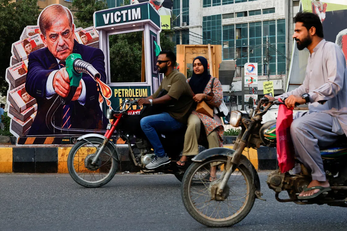 People on motorbikes ride past a portrait of Pakistani Prime Minister Shehbaz Sharif, set up in protest against rising fuel prices amid the U.S.-Iran conflict, ahead of the nationwide rollout of a government scheme offering a Rs100-per-litre subsidy to eligible motorcycles, rickshaws and vehicles up to 800cc, in Karachi, Pakistan, September 16, 2026. REUTERS/Akhtar Soomro TPX IMAGES OF THE DAY