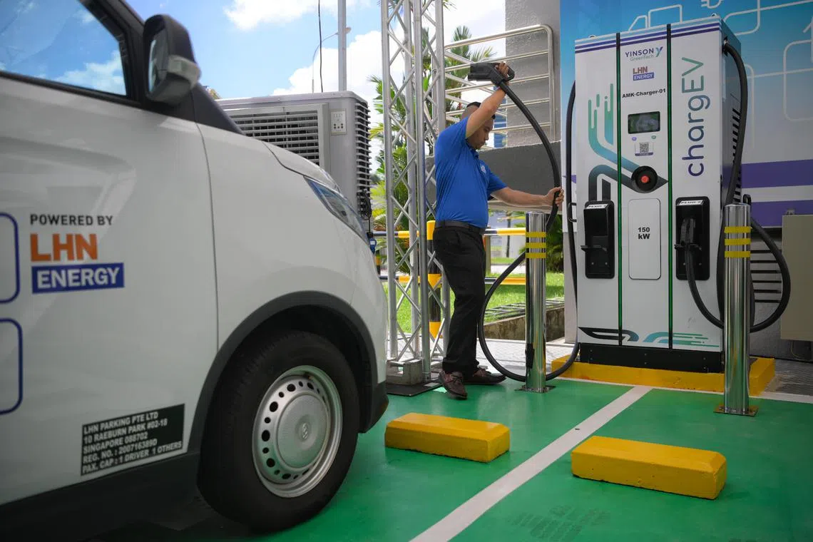 A man places a charging cable back into place after charging an electric vehicle (EV) at an EV charging system called chargeEV, launched by Yinson GreenTech and Yinson EV Charge Pte Ltd, is seen at 38 Ang Mo Kio Industrial Park after being officially unveiled on March 29, 2023. 