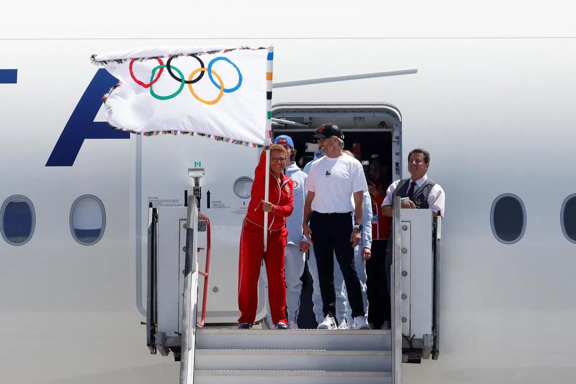 Los Angeles Mayor Karen Bass waves the official Olympic flag next to LA28 chairman Casey Wasserman.