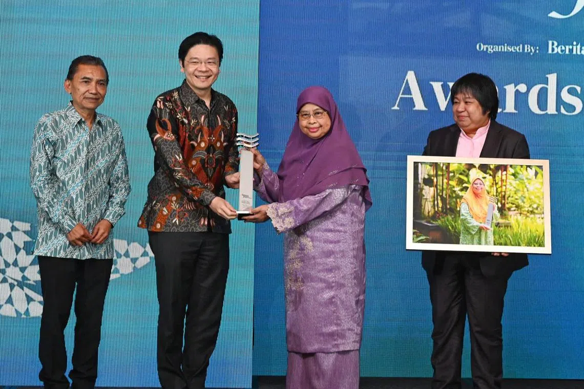 DPM Lawrence Wong (second left) giving the Berita Harian Achiever of the Year award to Associate Professor Hadijah Rahmat. With them is Berita Harian editor Sa'at Abdul Rahman (left) and SPH Media Trust Lay Lim Teo.