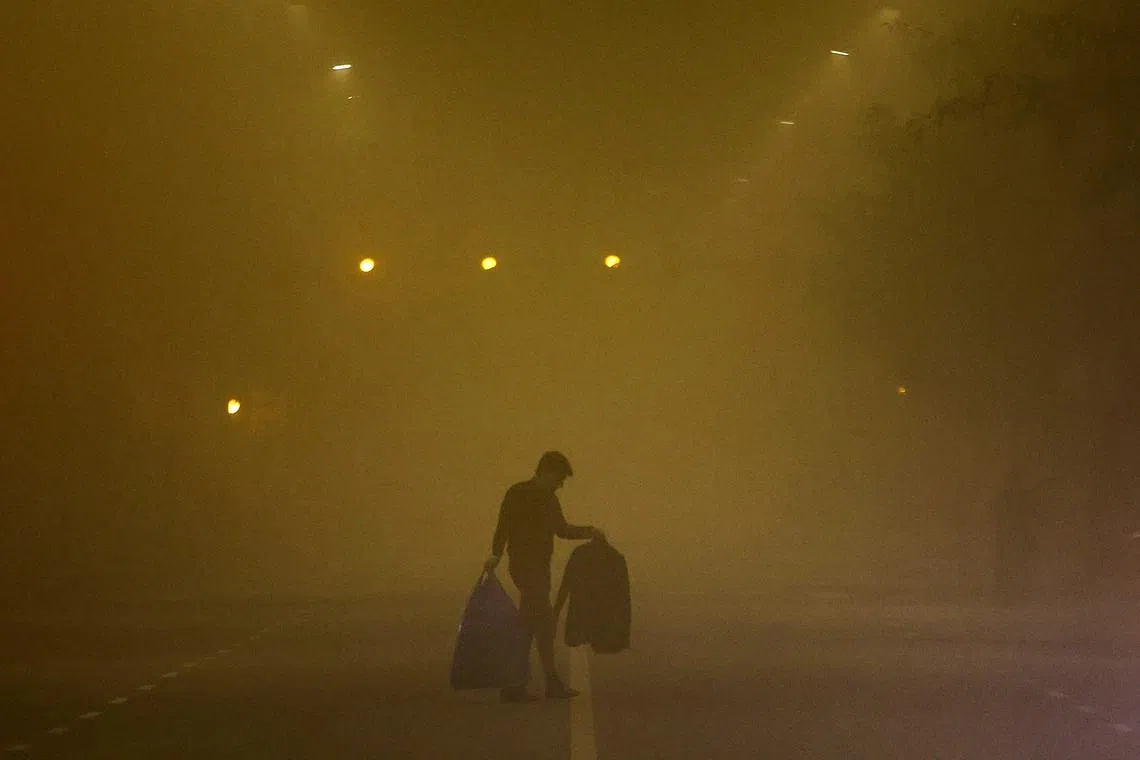 A man walks across a smoggy road on a cold winter morning in New Delhi, India, December 27, 2022. REUTERS/Anushree Fadnavis  REFILE - QUALITY REPEAT   TPX IMAGES OF THE DAY     