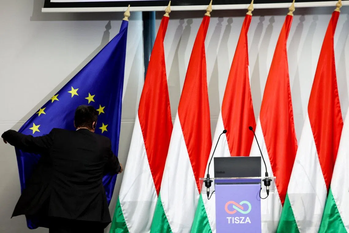 FILE PHOTO: A member of the staff adjusts a flag of the European Union placed next to a row of Hungarian flags before the press conference of election winner Peter Magyar in Budapest, Hungary, April 20, 2026. REUTERS/Bernadett Szabo/File Photo