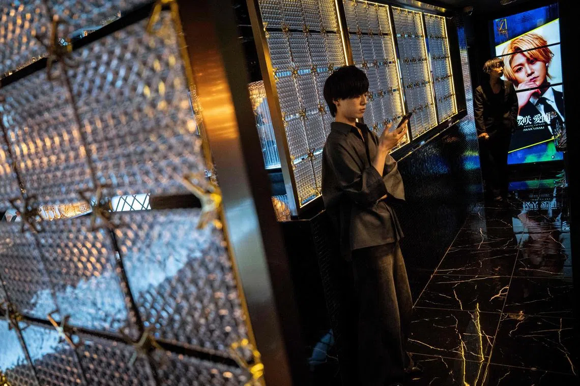A male host checking his phone while waiting for customers at a host club in the Kabukicho area of Tokyo.  