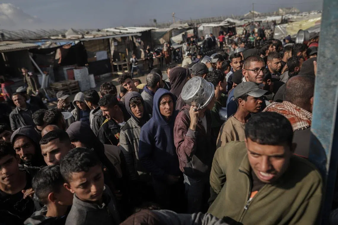 Palestinians wait to collect food handouts from a free kitchen run by volunteers in Khan Younis, central Gaza, on Jan 17.