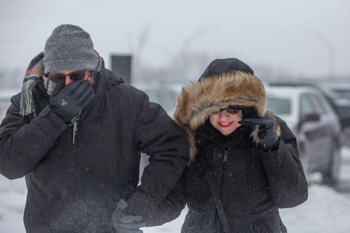 Residents walk through the snow in West Des Moines, Iowa, US, on Saturday, Jan. 13, 2024. A powerful winter storm will bring heavy snow and blizzard conditions to the Midwest and Great Lakes regions starting Saturday. In Iowam, Republican presidential hopefuls Ron DeSantis, Nikki Haley and Donald Trump canceled some weekend campaign events. Photographer: Rachel Mummey/Bloomberg
