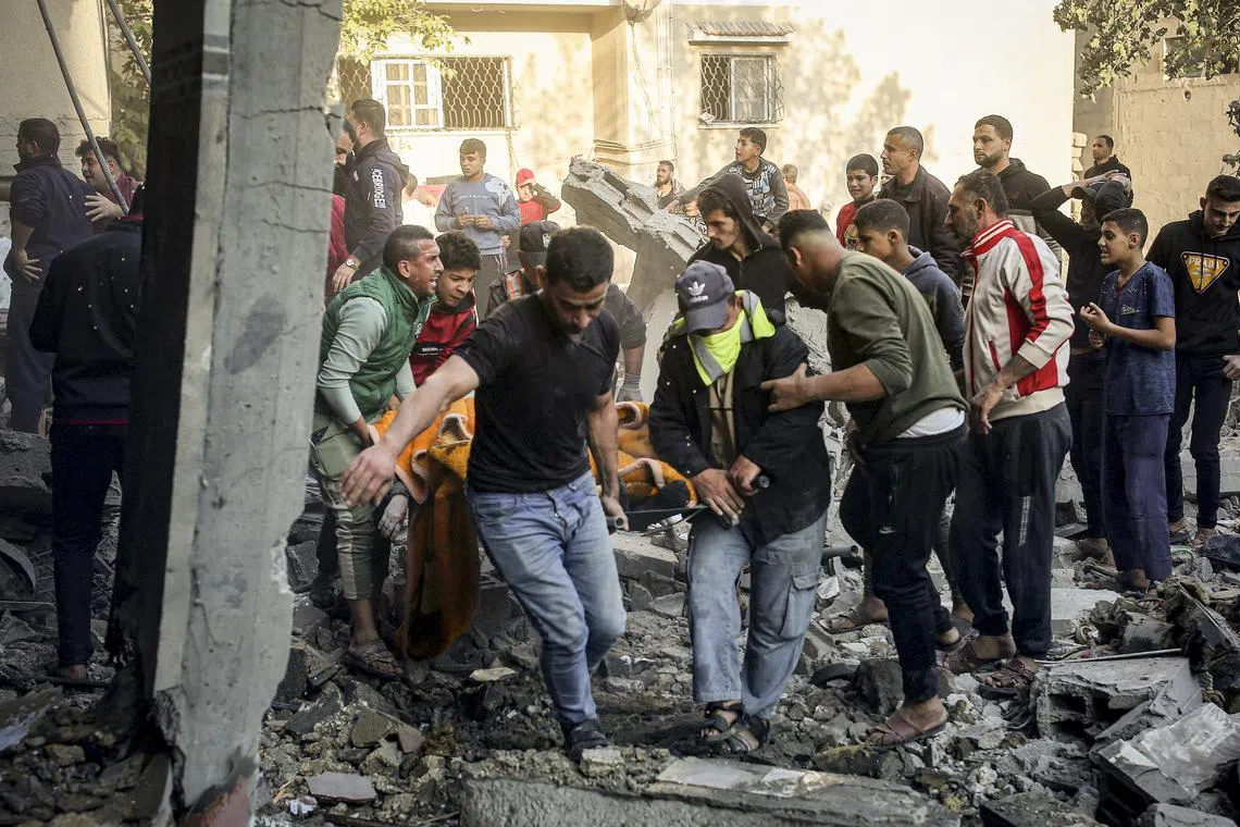 Palestinians in Khan Younis carry the body of a victim pulled from the rubble of a destroyed house in the southern Gaza Strip on Dec 4, 2023.