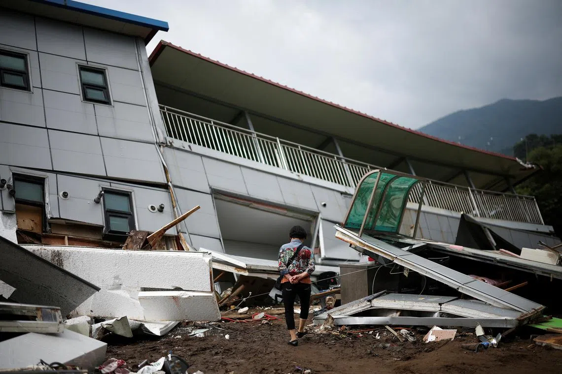 A woman inspecting damage around a collapsed building in the aftermath of torrential rain, in Gapyeong, South Korea, on July 21, 2025. 