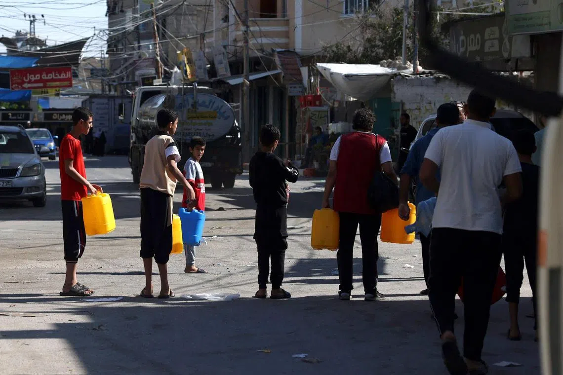 Palestinians queue for water at the Rafah refugee camp, in the southern of Gaza Strip on Octobers 15, 2023. Convoys of humanitarian aid stacked up near Egypt's border with the Gaza Strip on Sunday, unable to enter the Palestinian enclave being bombarded by Israel, witnesses told AFP. Alarm has grown about a wider humanitarian crisis in Gaza where Israel has cut off water, food and power, vowing to maintain the complete siege until all hostages are freed. (Photo by MOHAMMED ABED / AFP)