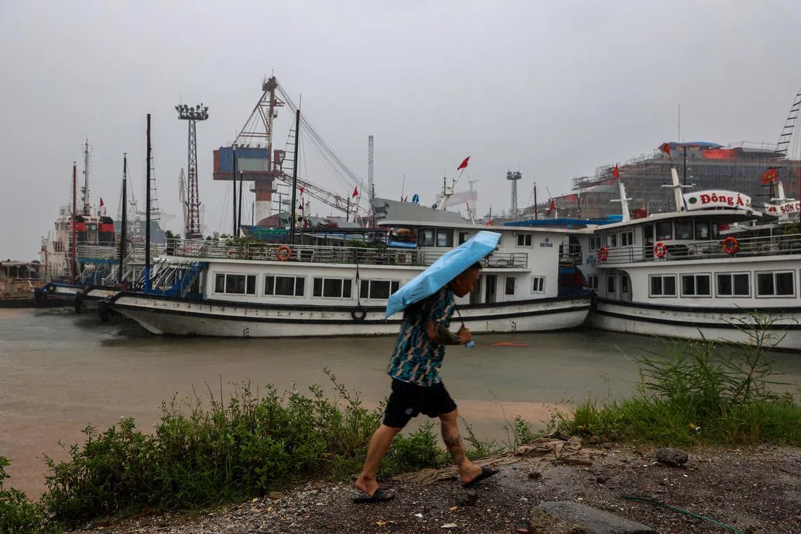 A man holding an umbrella near docked tourist boats, as Typhoon Wipha approaches, at Halong Bay, Quang Ninh province on July 21. 