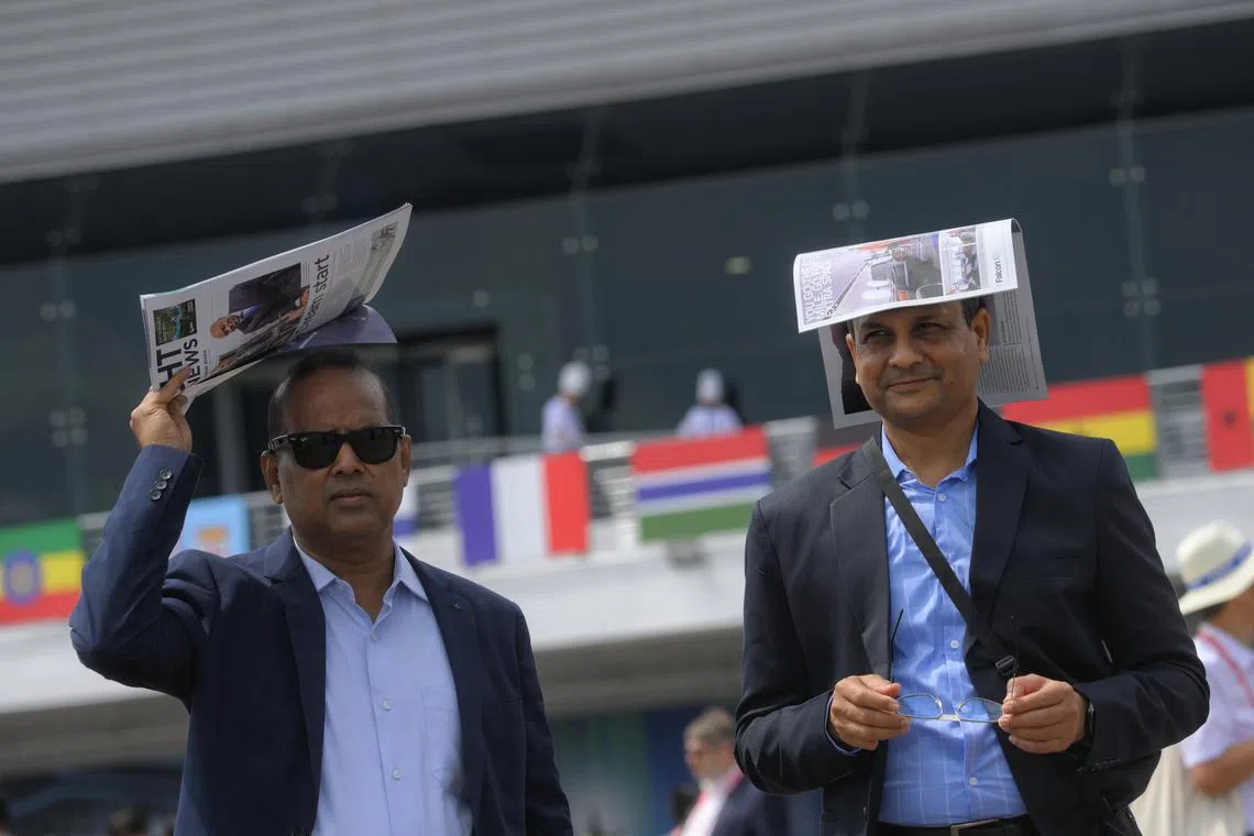 Spectators shielding themselves from the sun during the aerial display at the Singapore Airshow on Feb 21, 2024.