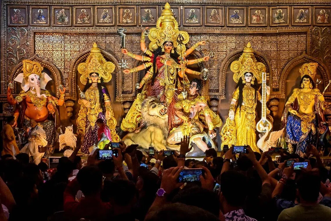 Devotees take photographs as they visit a 'Pandal' (temporary structure for worship) with an idol of the Hindu goddess Durga on the eve of the Durga Puja festival in Kolkata on Sept 27, 2025. 