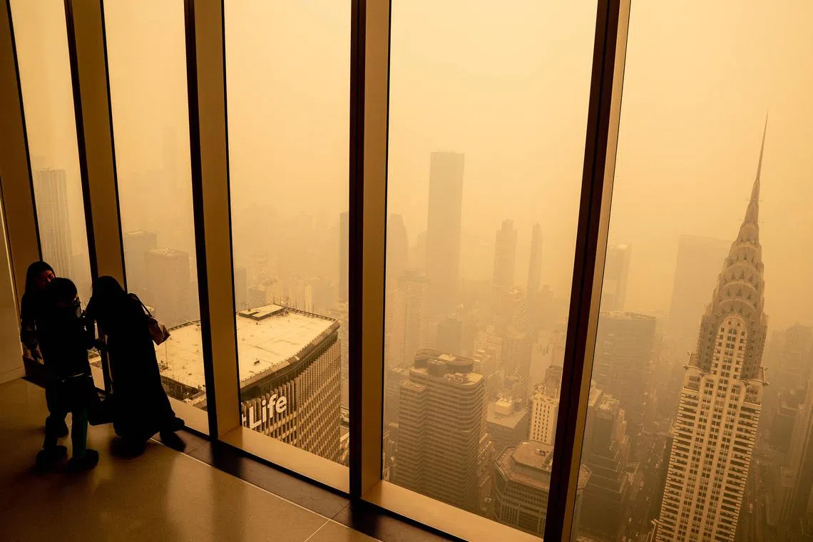 Visitors at Summit One Vanderbilt looking out at a smoke shrouded Manhattan as wildfires in Canada continue to blanket the city on June 7, 2023 in New York City. 