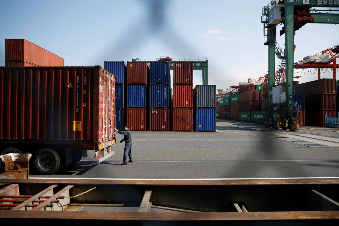 A man works between shipping containers at a port in Tokyo, Japan, March 22, 2017. REUTERS/Issei Kato/File Photo