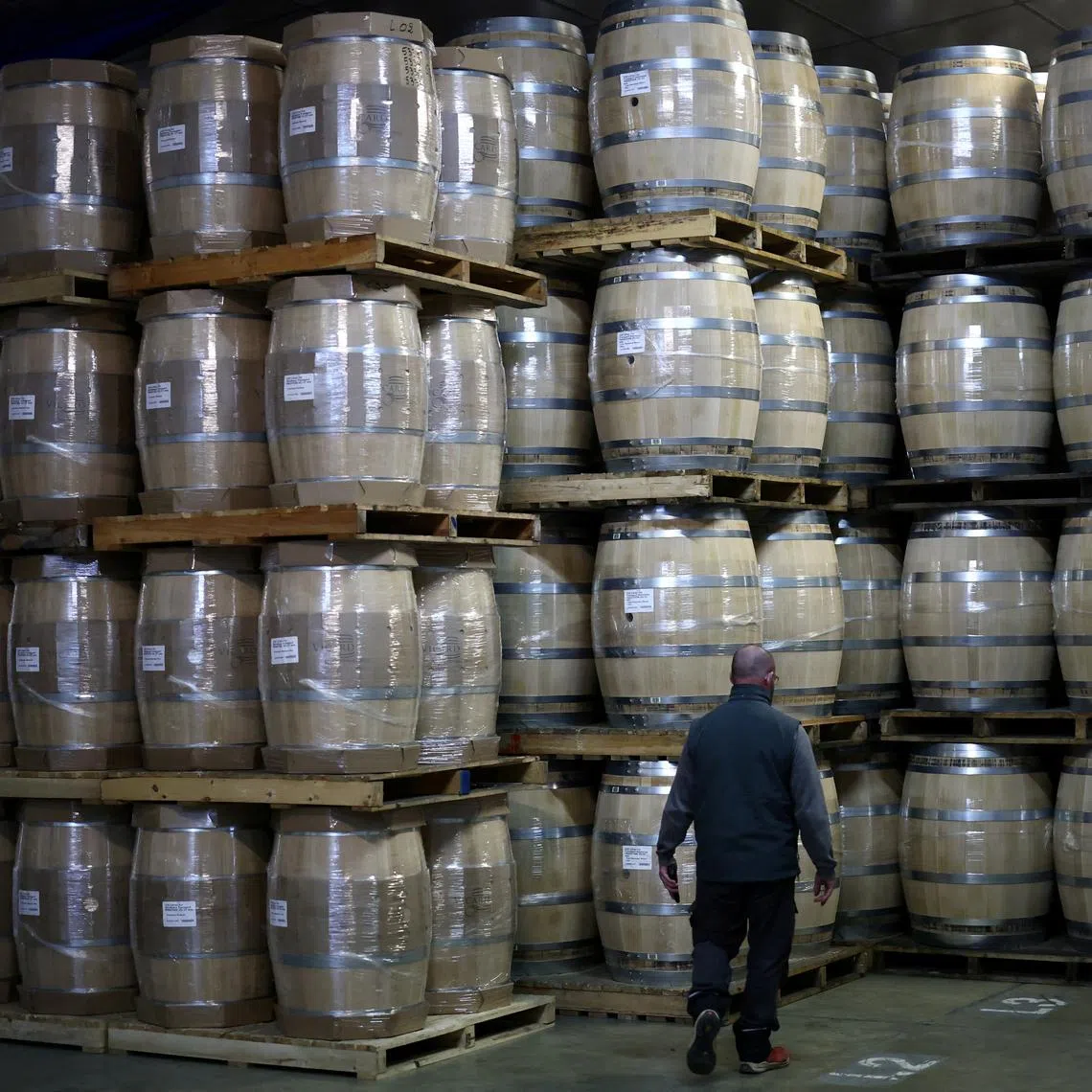 FILE PHOTO: An employee walks past oak barrels at the Tonnelleries Vicard cooperage in Cognac, France, April 3, 2025. REUTERS/Stephane Mahe/File Photo