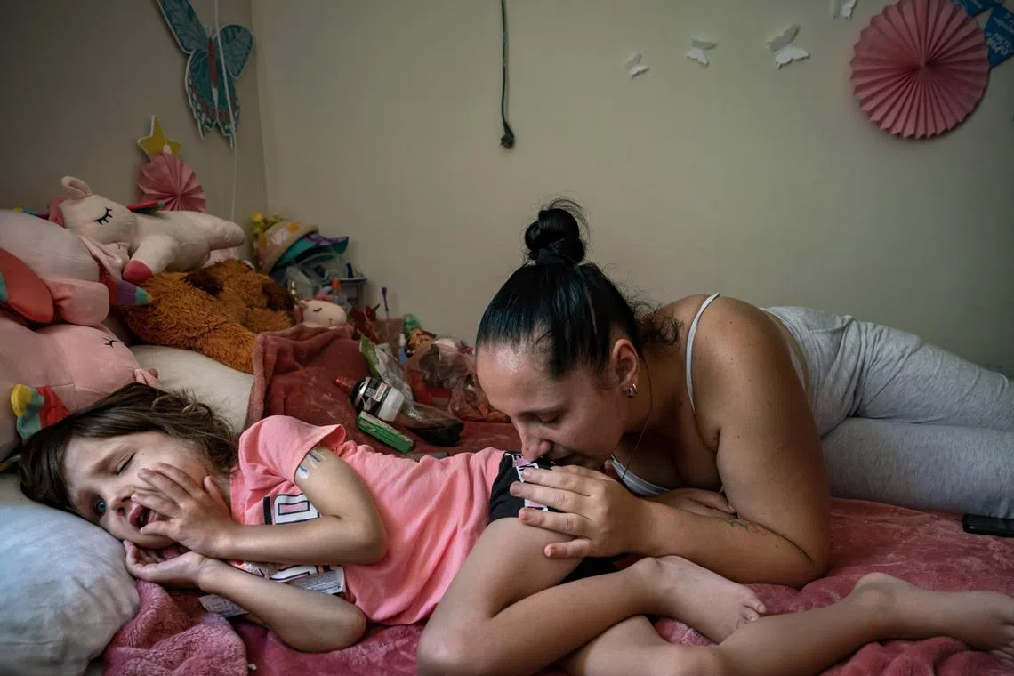Natalia Kryvolapchuk comfort her cancer-stricken daughter Sonya Liakh, 6, as she lay semi-conscious after returning from an hospitalÕs intensive care unit, at the City of Goodness, a palliative care shelter in Chernivtsi, Ukraine, July 29, 2024. The daunting health challenges facing sick and disabled children in Ukraine are a cruel reminder that the warÕs tentacles stretch far beyond the front line. (Lynsey Addario/The New York Times) Ñ NO SALES